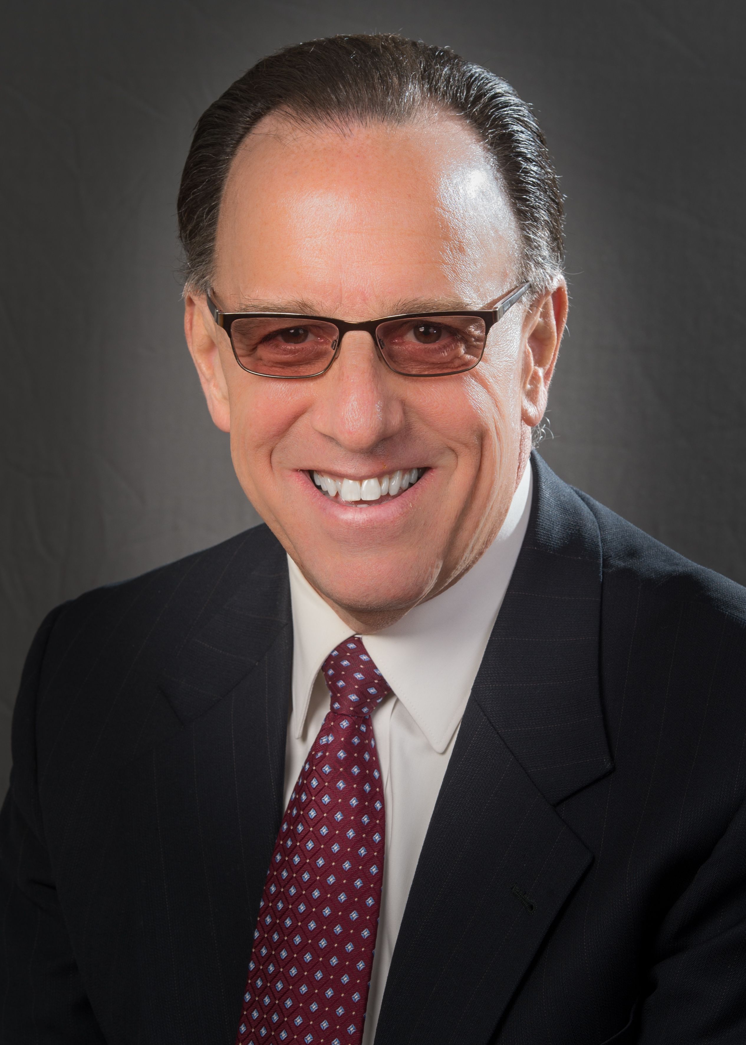Theodore Strange, MD, wearing shaded glasses and a maroon tie